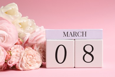 International Women's day - 8th of March. Wooden block calendar and beautiful flowers on pink background