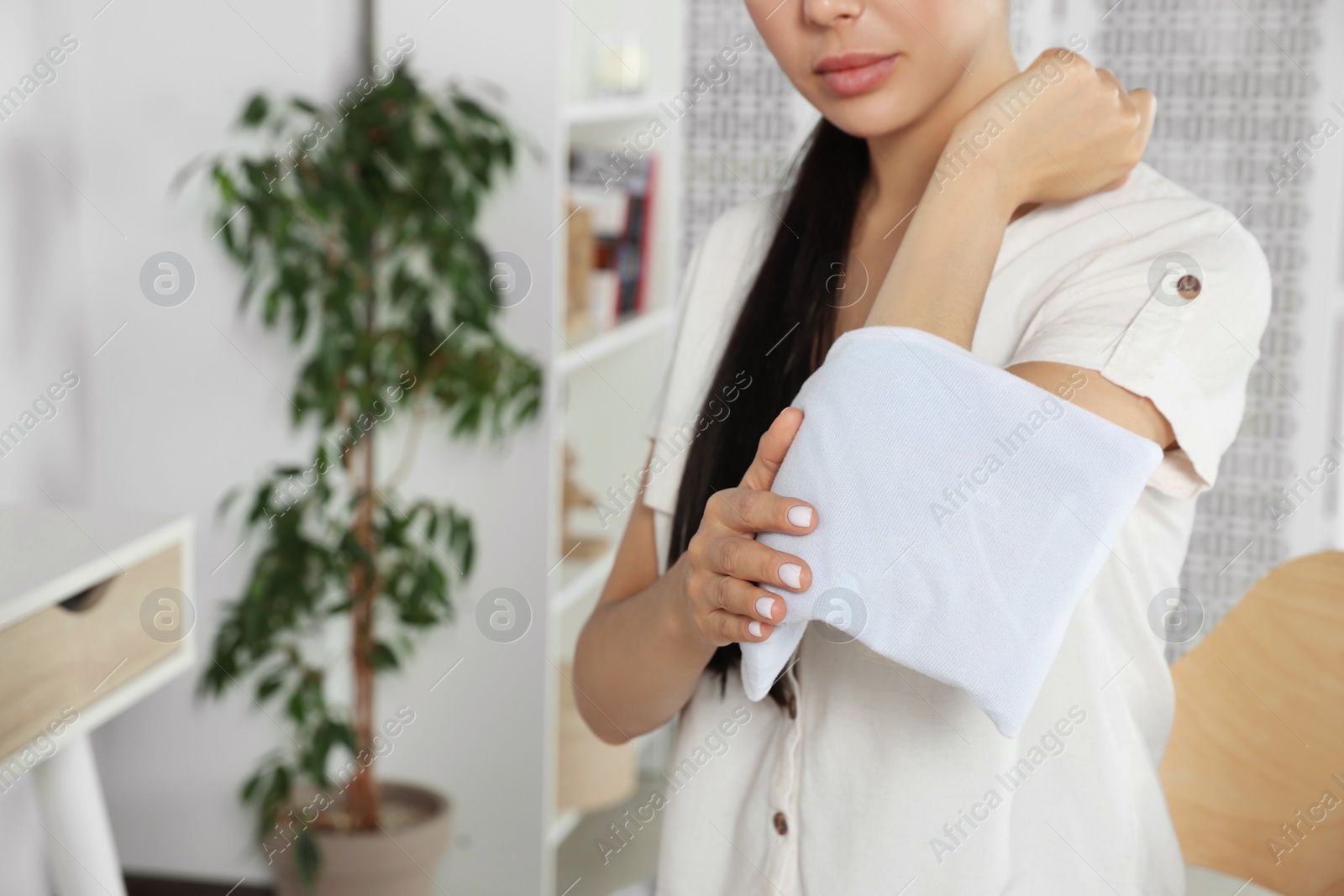 Photo of Young woman using heating pad at home, closeup