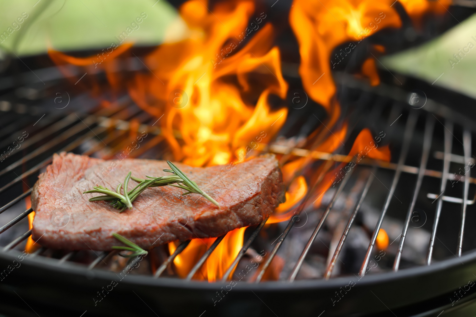 Photo of Tasty meat on barbecue grill with fire flames outdoors, closeup