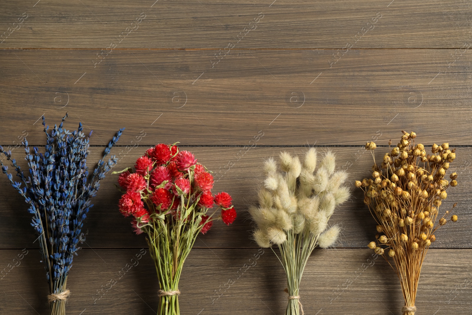 Photo of Bunches of beautiful dried on wooden table, flat lay. Space for text