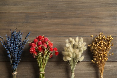 Bunches of beautiful dried on wooden table, flat lay. Space for text