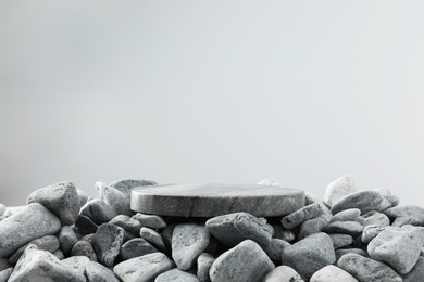 Photo of Presentation for product. Stone and pebbles on grey background. Space for text