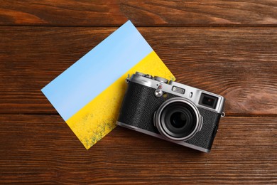 Photo of Vintage photo camera and beautiful printed picture on wooden table, flat lay. Creative hobby