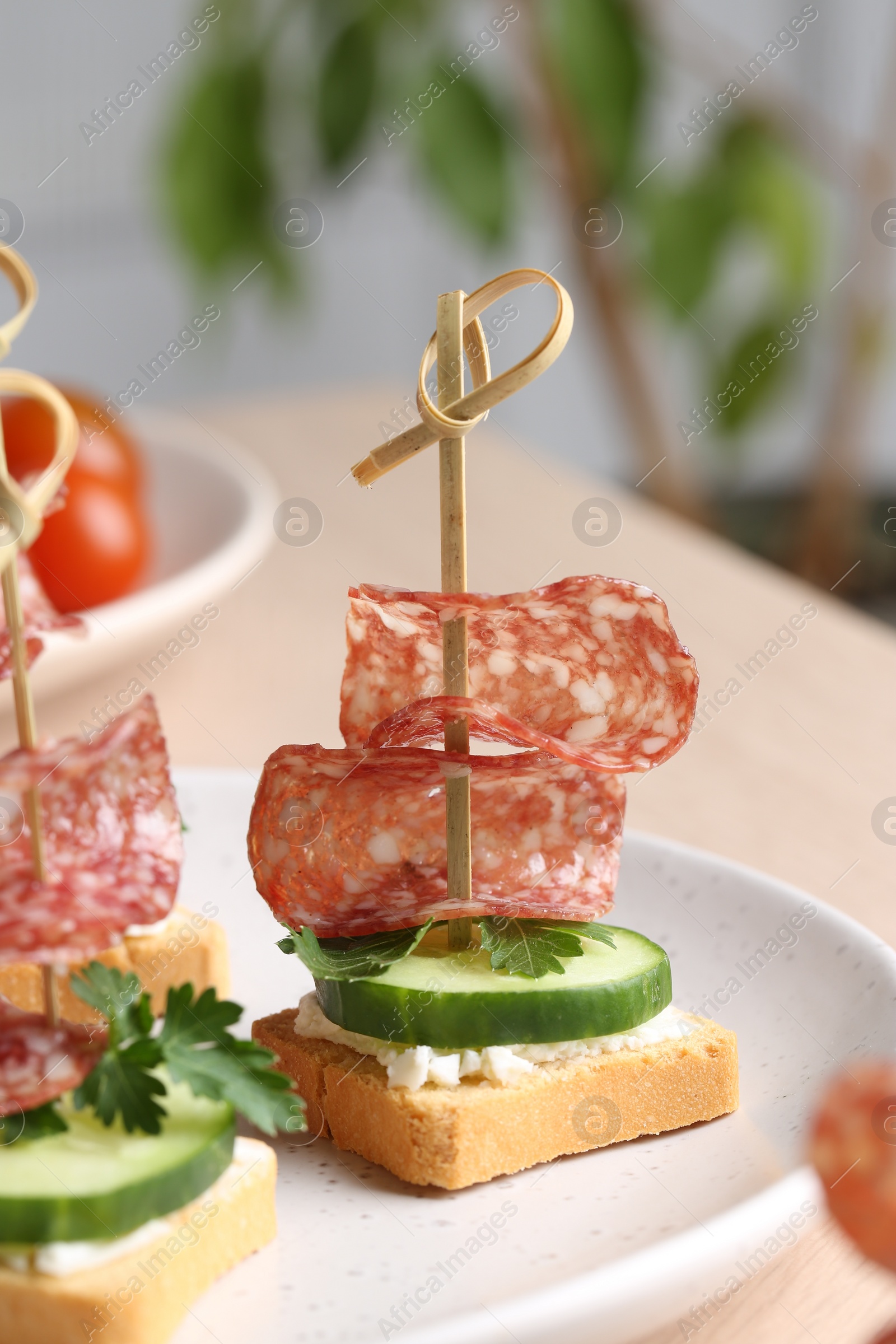 Photo of Tasty canapes with salami, cucumber and cream cheese on table, closeup