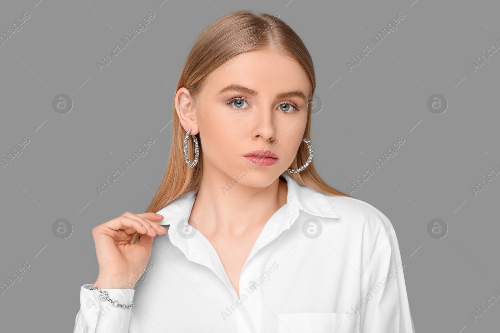 Photo of Beautiful young woman with elegant jewelry on gray background