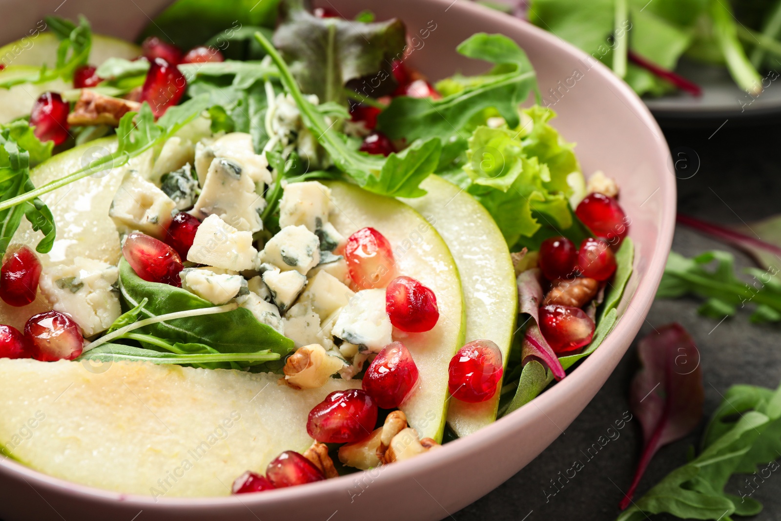 Photo of Tasty salad with pear slices and pomegranate seeds on table, closeup