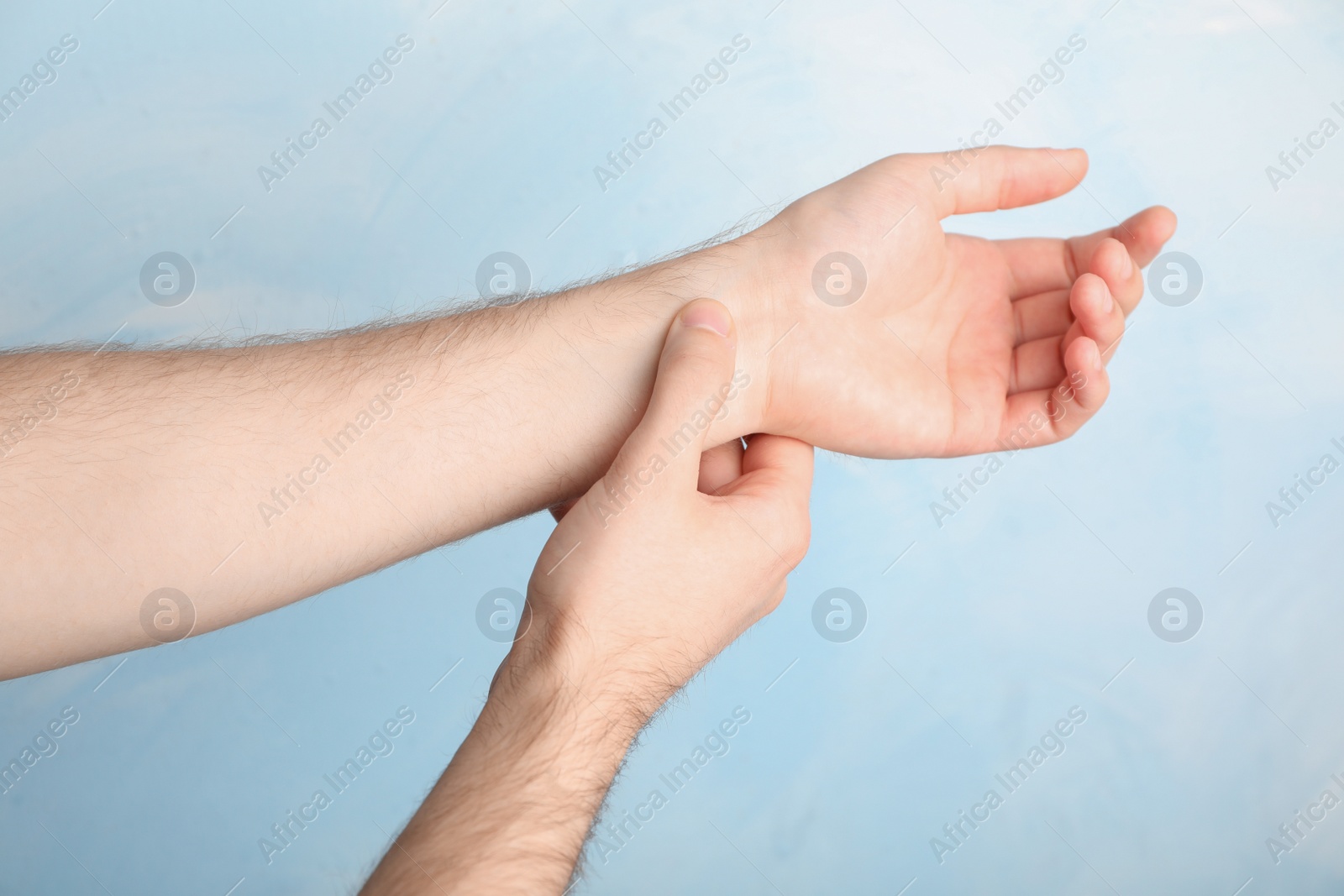 Photo of Man checking pulse on color background, closeup