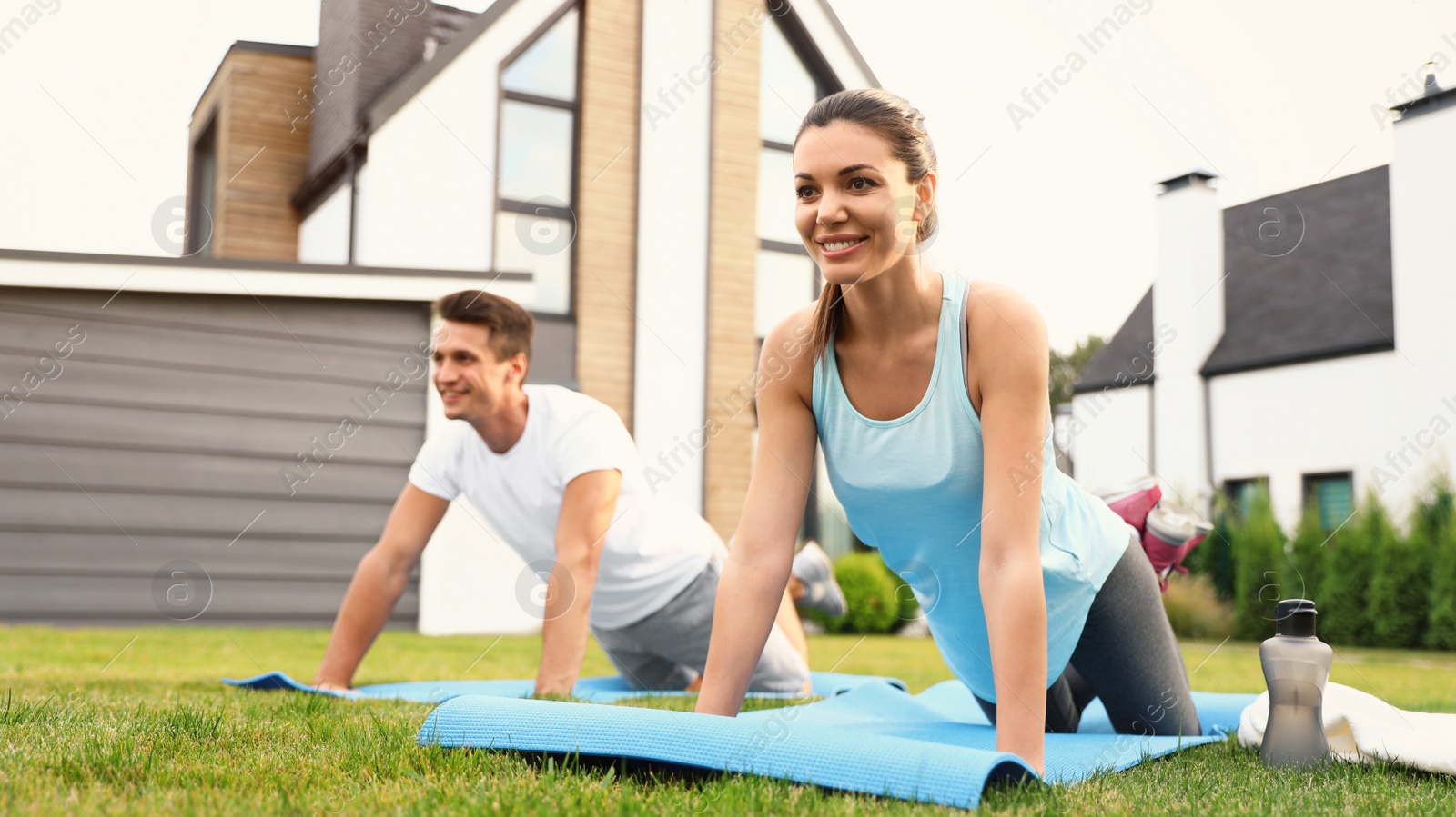 Photo of Sporty couple practicing morning yoga at backyard. Healthy lifestyle