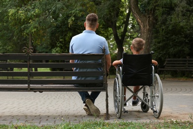 Father with his son in wheelchair at park