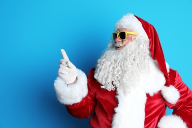 Authentic Santa Claus wearing sunglasses on color background