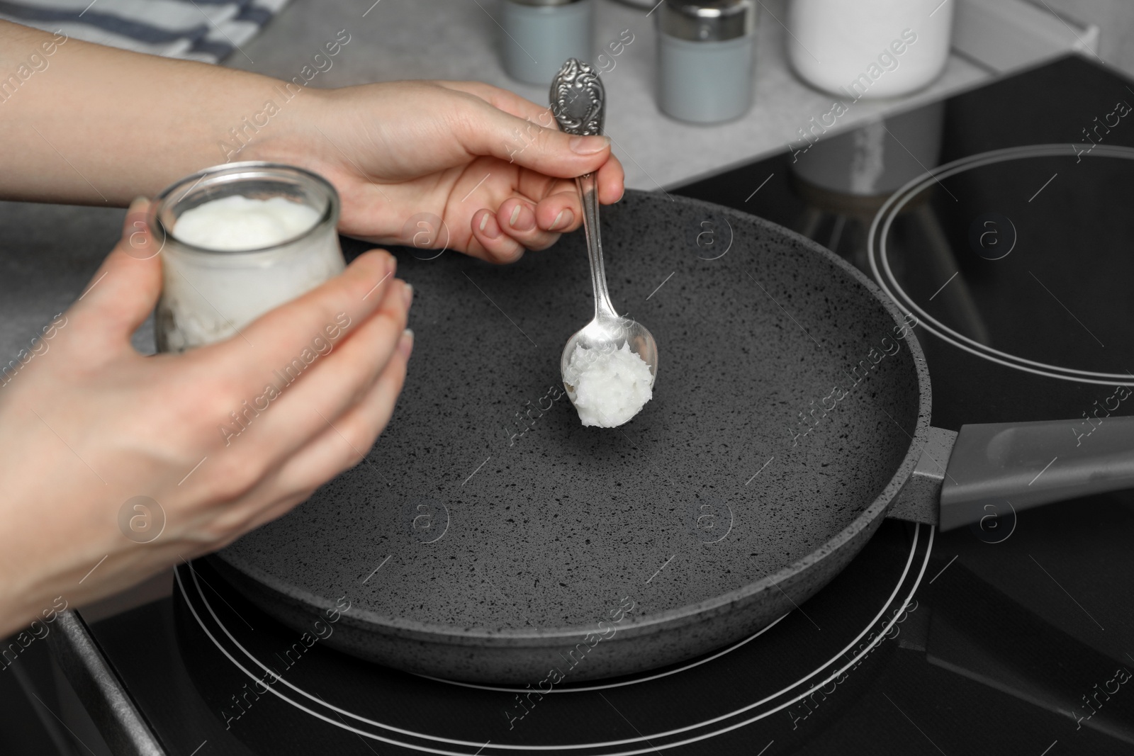 Photo of Woman cooking with coconut oil on induction stove, closeup