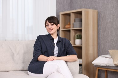 Photo of Beautiful young housewife on sofa at home