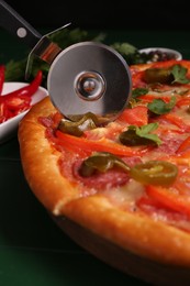 Cutting delicious pizza Diablo at wooden table, closeup