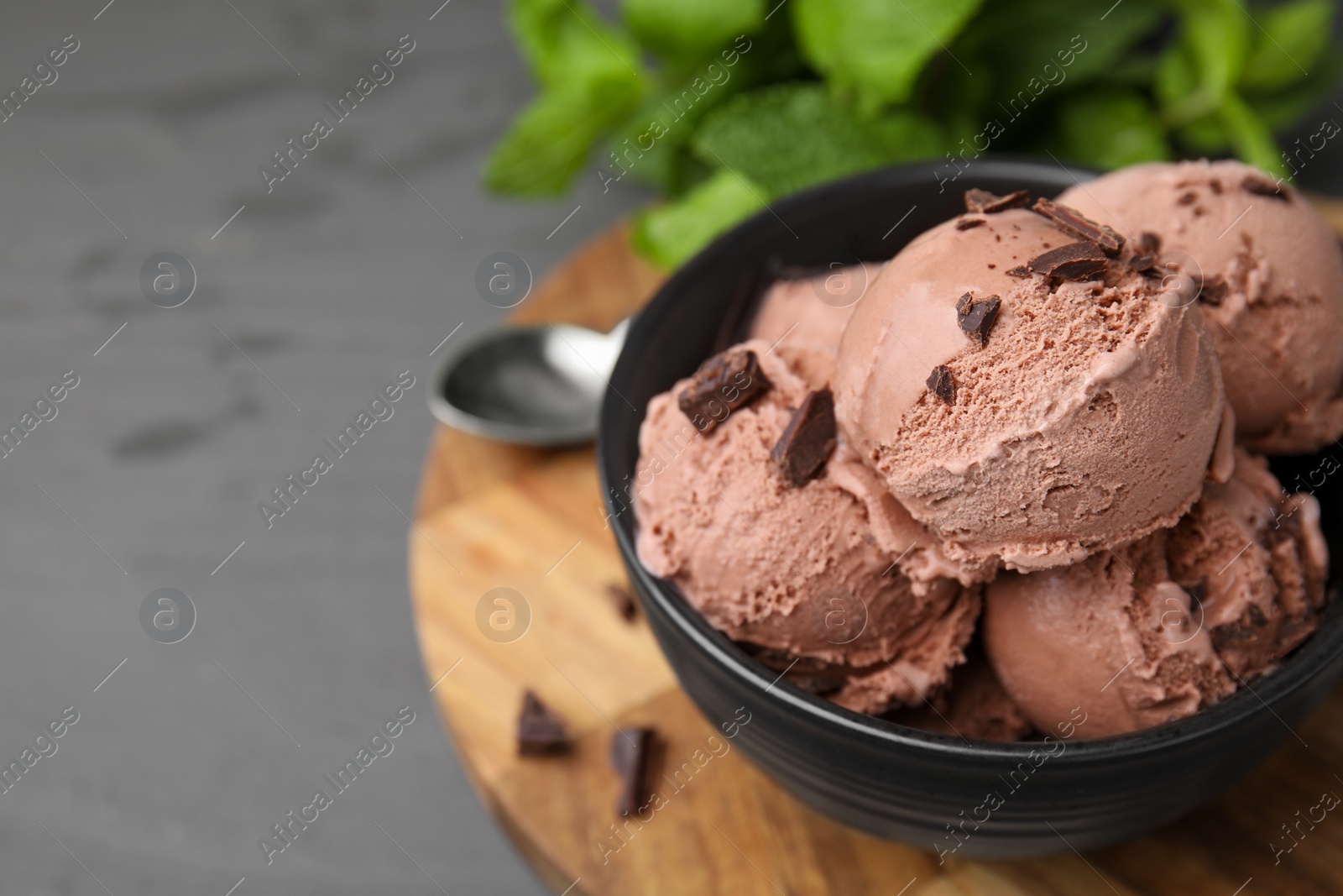 Photo of Bowl with tasty chocolate ice cream on grey wooden table, closeup. Space for text