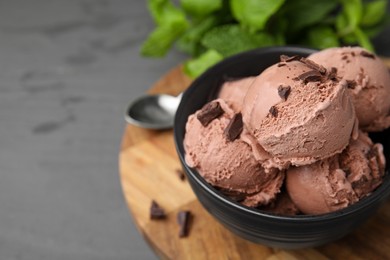 Bowl with tasty chocolate ice cream on grey wooden table, closeup. Space for text