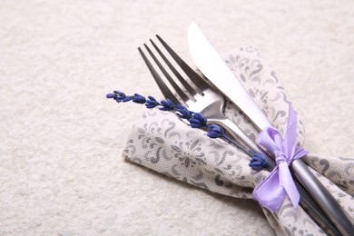 Photo of Cutlery, napkin and preserved lavender flower on white textured table, closeup. Space for text