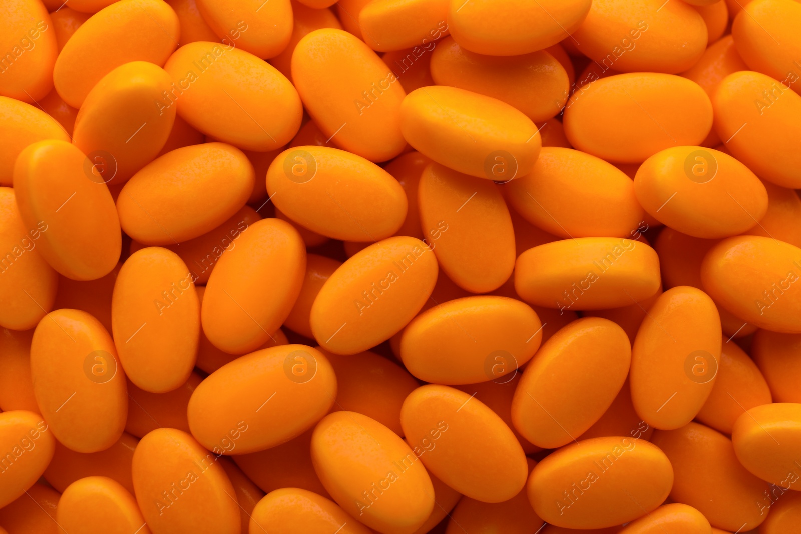 Photo of Tasty orange dragee candies as background, top view