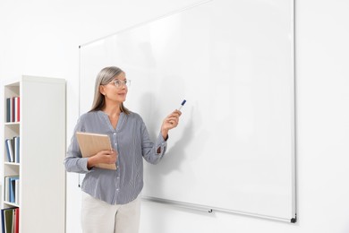 Professor giving lecture near whiteboard in classroom, space for text