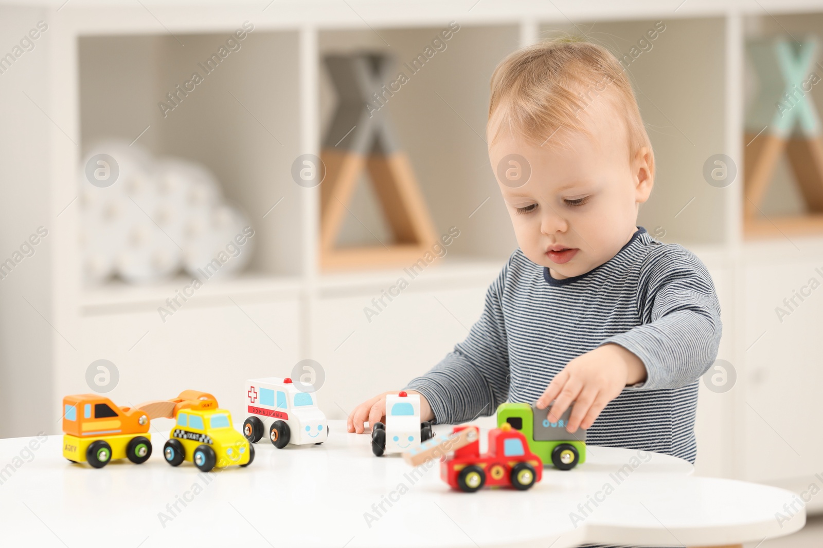 Photo of Children toys. Cute little boy playing with toy cars at white table in room, space for text