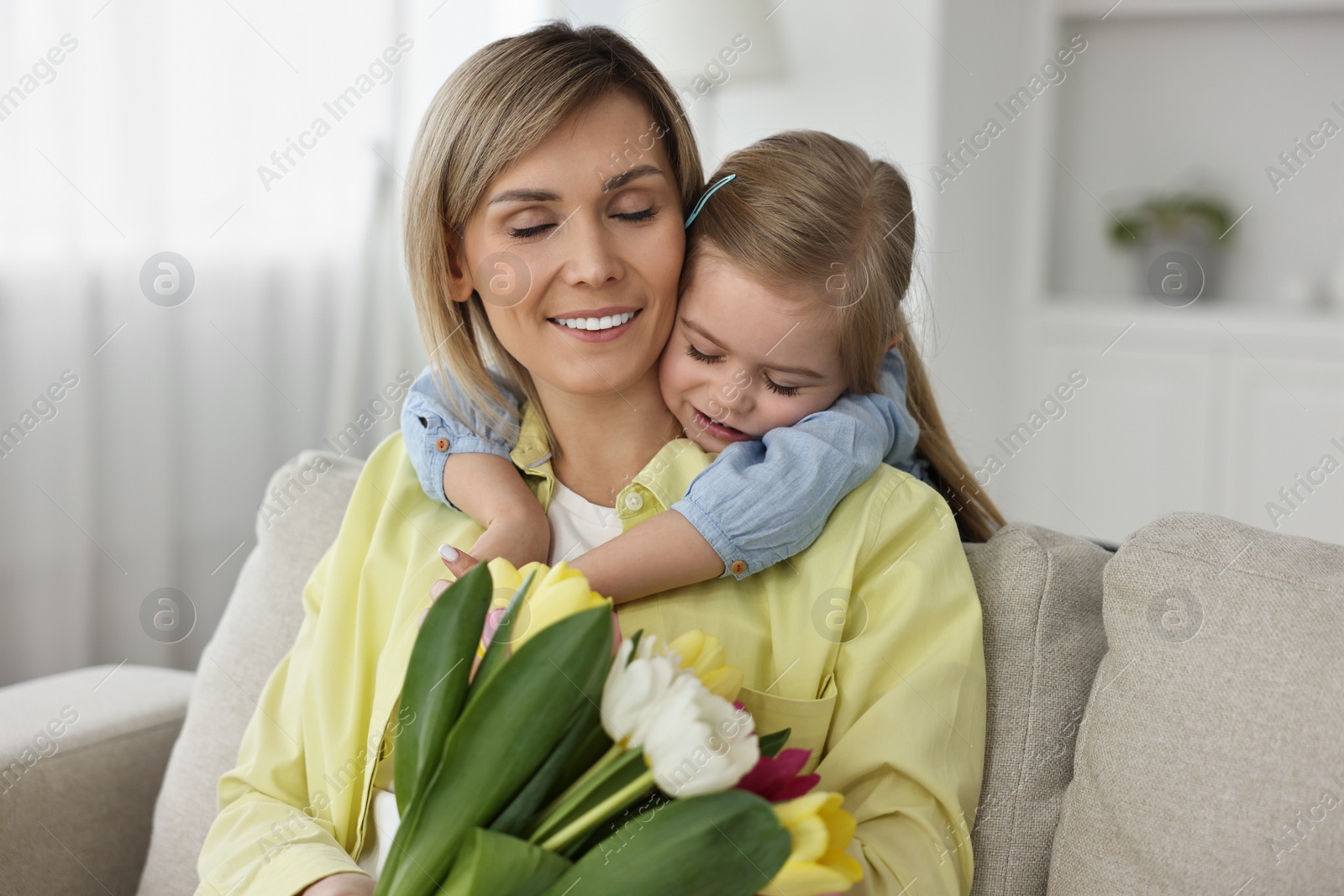 Photo of Little daughter congratulating her mom with bouquet of beautiful tulips at home. Happy Mother's Day