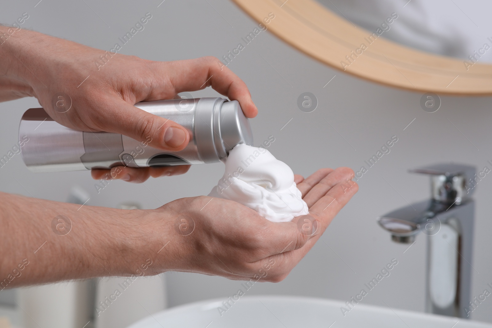 Photo of Man applying shaving foam onto hand in bathroom, closeup