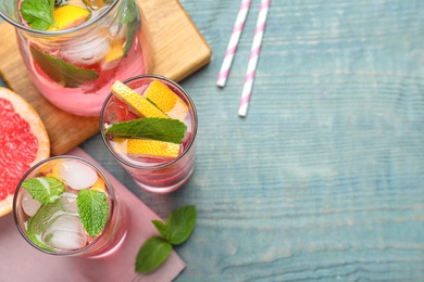 Photo of Flat lay composition of delicious grapefruit lemonade with soda water and mint on blue wooden table, space for text. Fresh summer cocktail