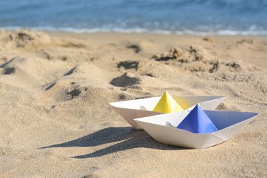 Two paper boats near sea on sunny day, space for text