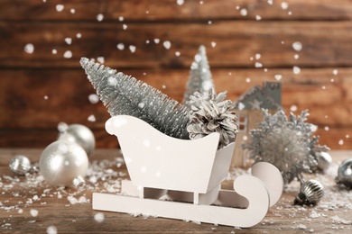 Photo of Beautiful Christmas composition with miniature sleigh on wooden table