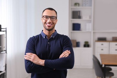 Photo of Smiling young businessman with eyeglasses in modern office. Space for text