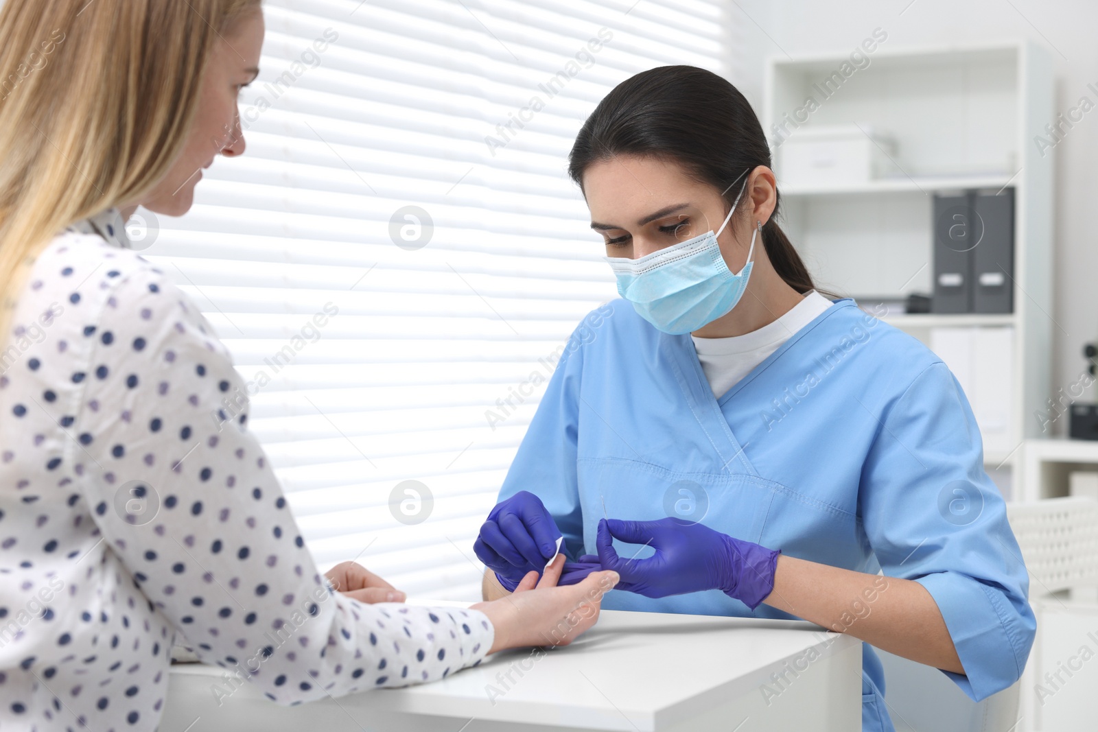 Photo of Laboratory testing. Doctor taking blood sample from patient at white table in hospital