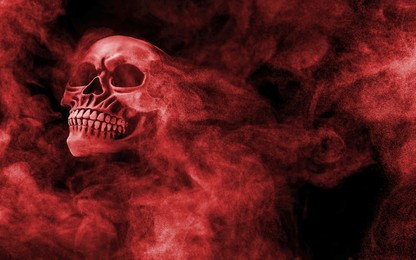 Image of Scary skull emerging from smoke in darkness