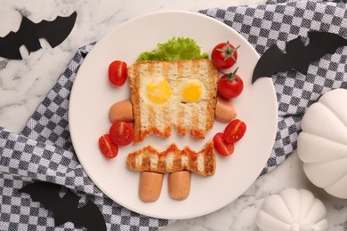 Cute monster sandwich with cherry tomatoes, fried eggs and sausages on white marble table, flat lay. Halloween snack