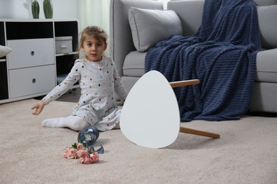 Child and broken ceramic vase on floor at home