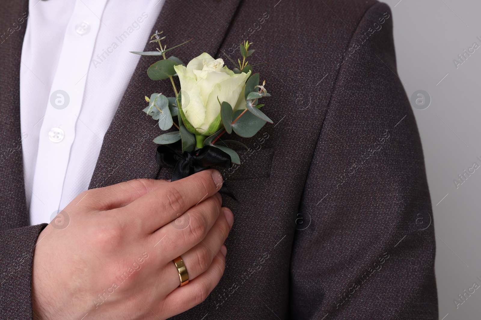 Photo of Groom with boutonniere on light grey background, closeup. Wedding accessory