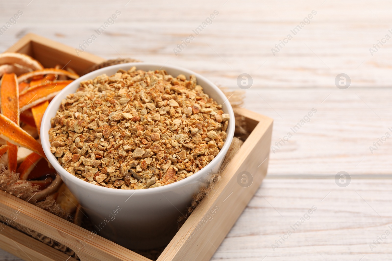 Photo of Dried orange seasoning zest and peel on white wooden table, space for text