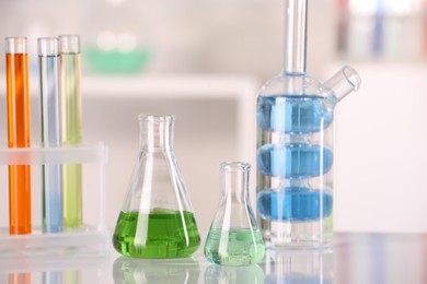 Photo of Laboratory analysis. Different glassware with liquids on white table against blurred background