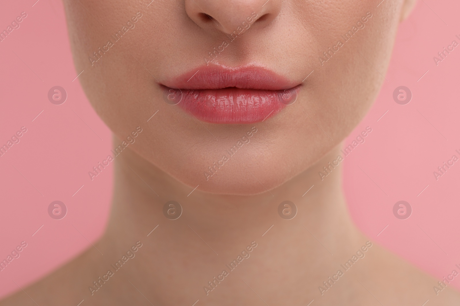 Photo of Young woman with beautiful full lips on pink background, closeup