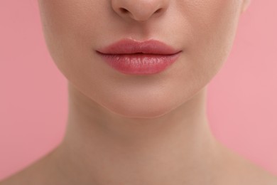 Young woman with beautiful full lips on pink background, closeup