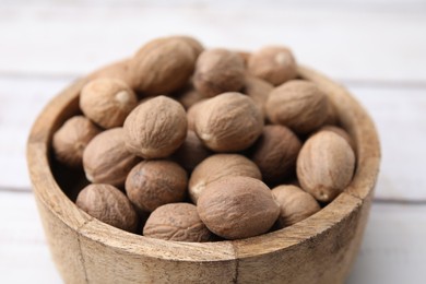 Photo of Whole nutmegs in bowl on light table, closeup