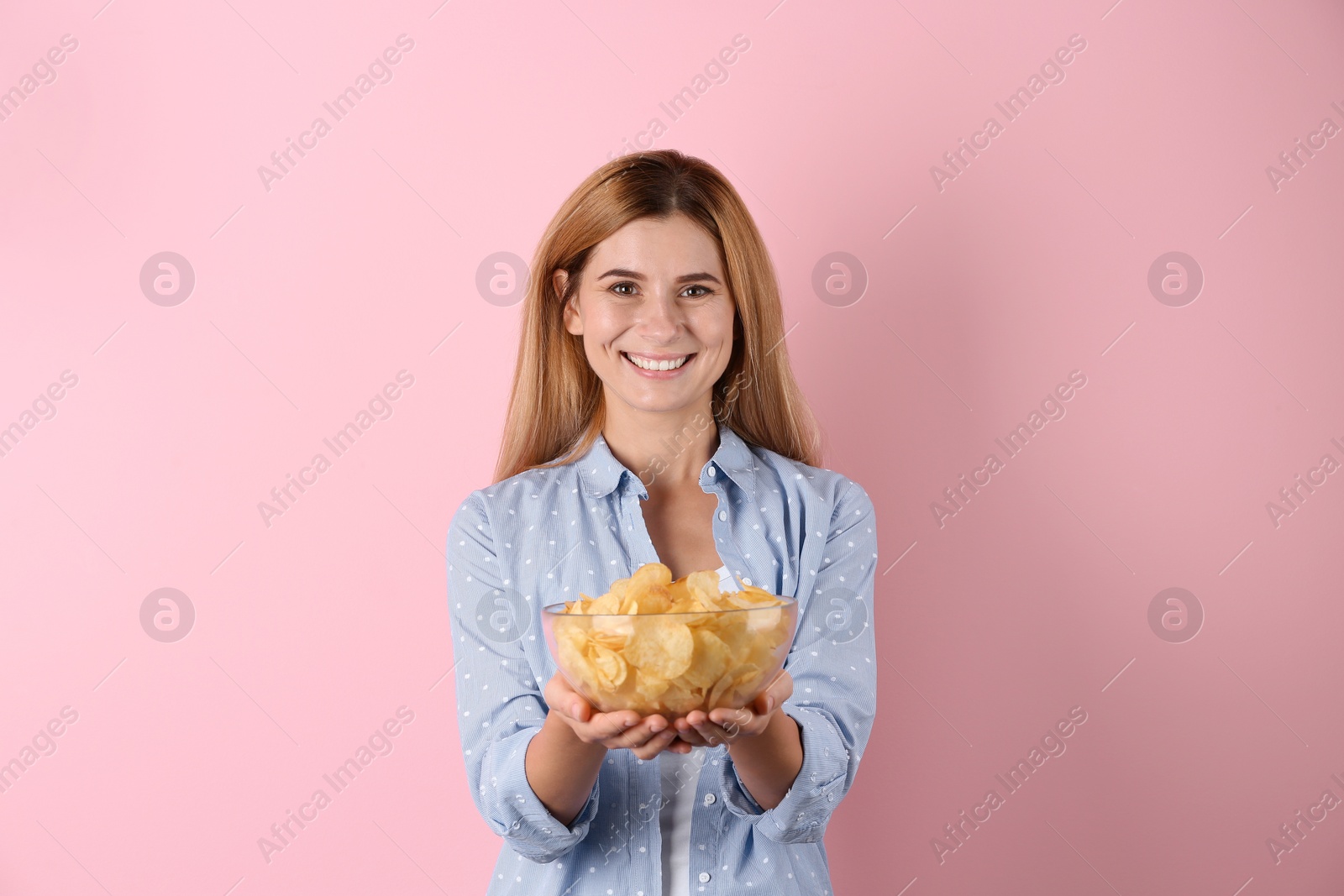 Photo of Woman with bowl of potato chips on color background