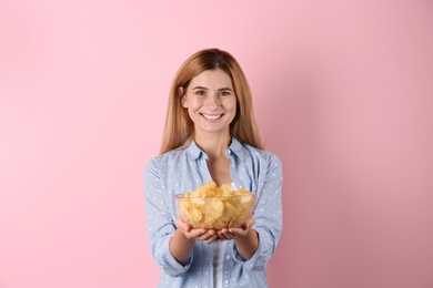 Woman with bowl of potato chips on color background