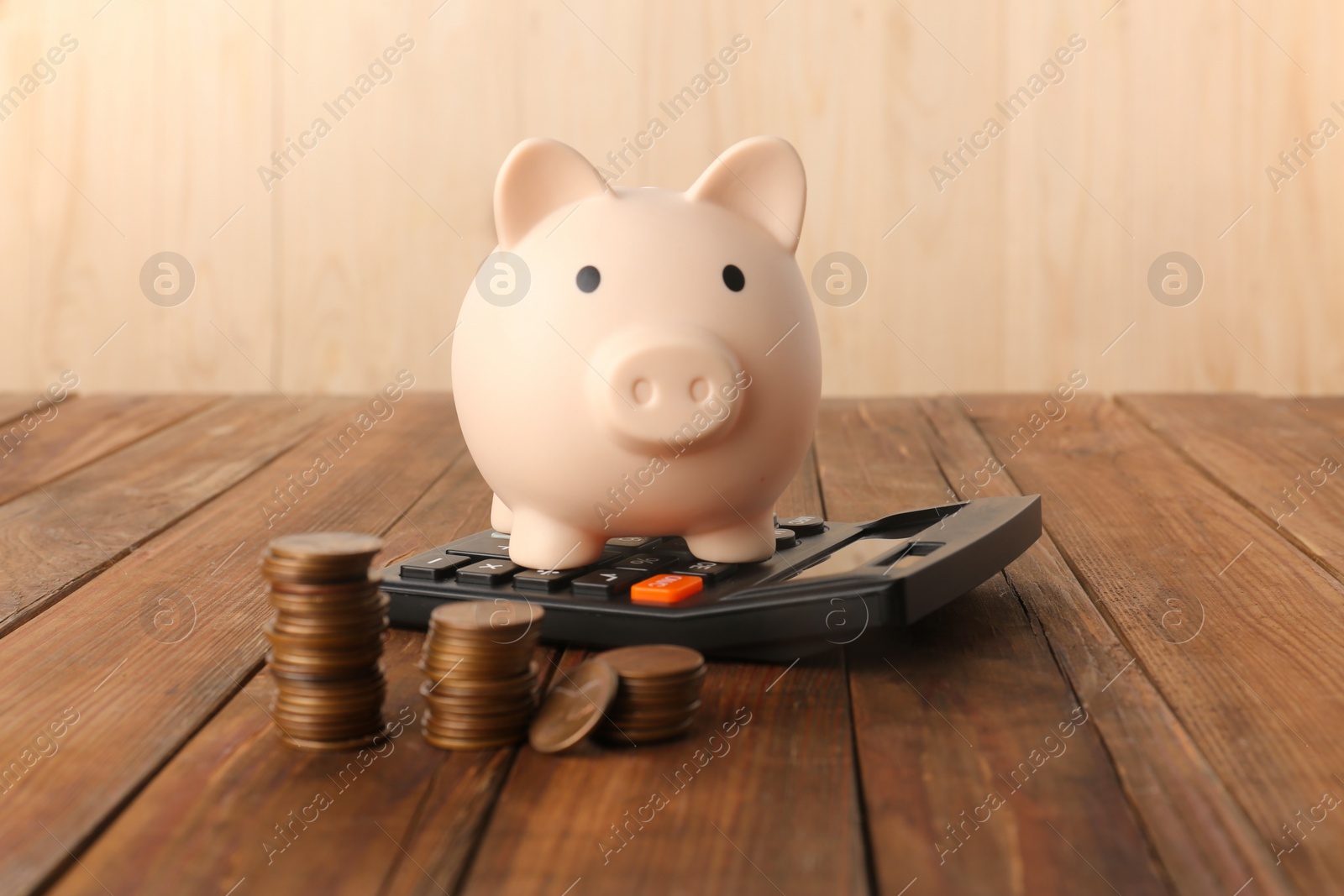 Photo of Calculator, coins and piggy bank on wooden table