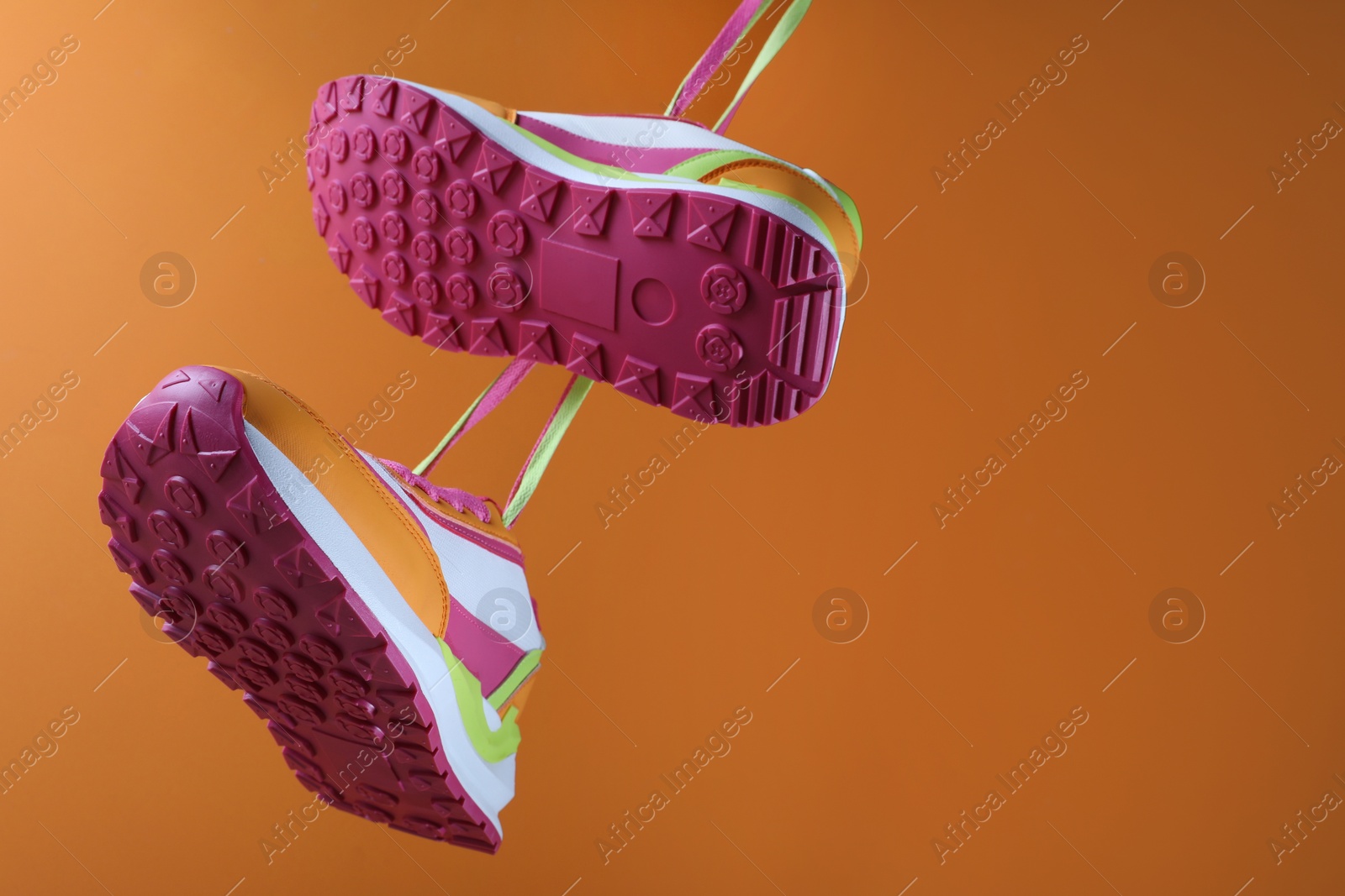 Photo of Pair of stylish sneakers on orange background. Space for text