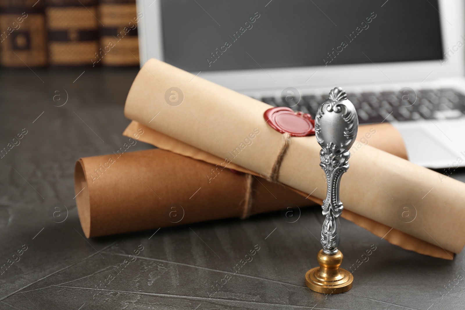 Photo of Notary's public pen and sealed documents near laptop on grey stone table