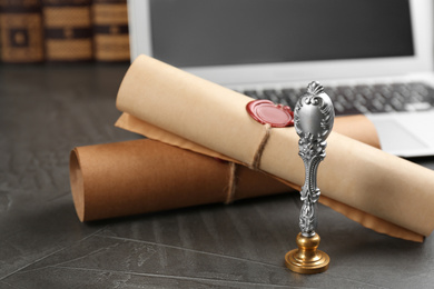 Photo of Notary's public pen and sealed documents near laptop on grey stone table