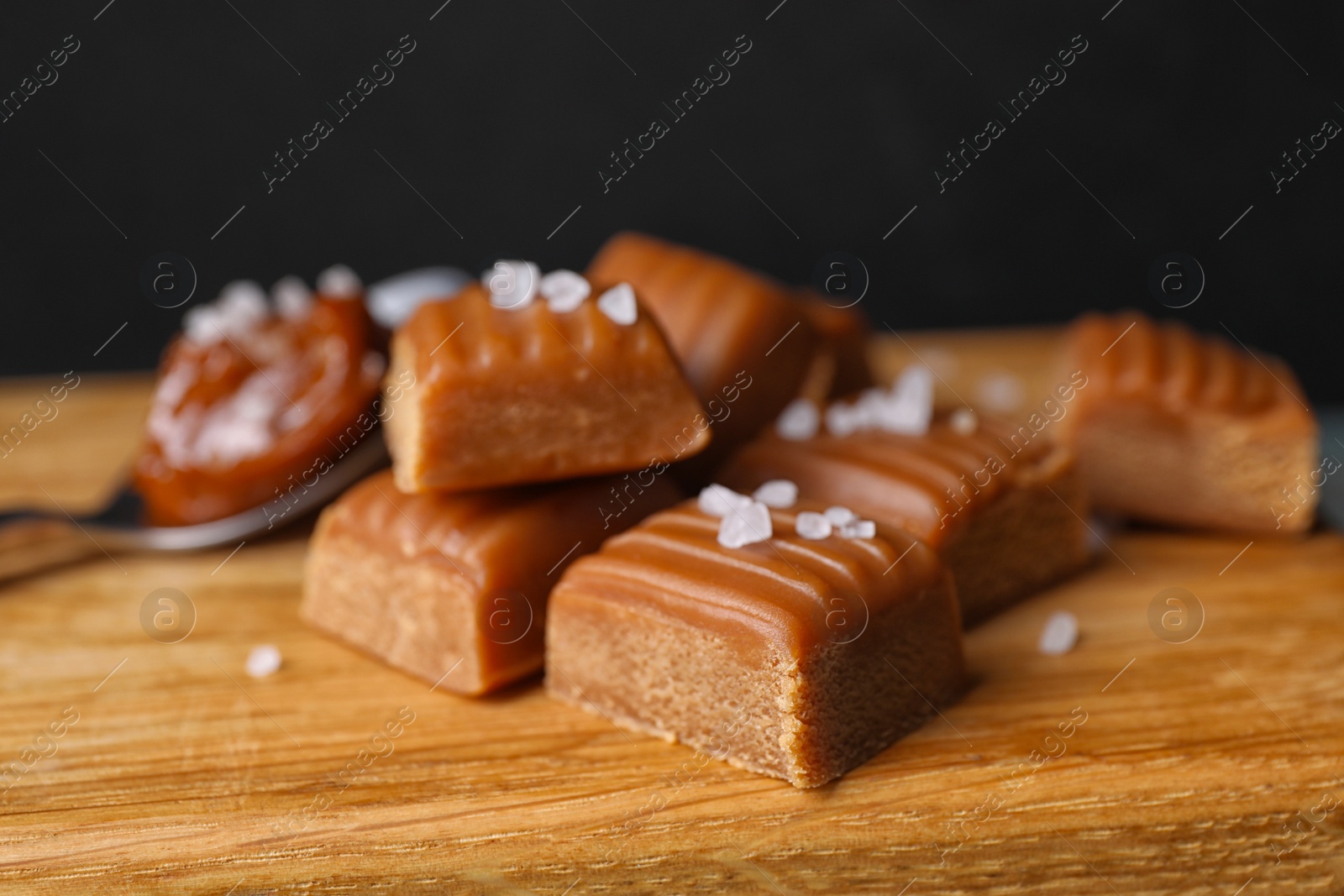 Photo of Delicious salted caramel on wooden board, closeup