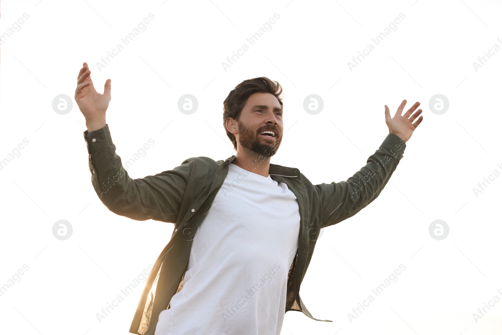 Photo of Feeling freedom. Happy man with wide open arms against sky outdoors, low angle view