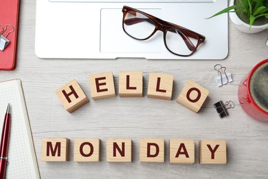 Cubes with message Hello Monday and office stationery on wooden desk, flat lay