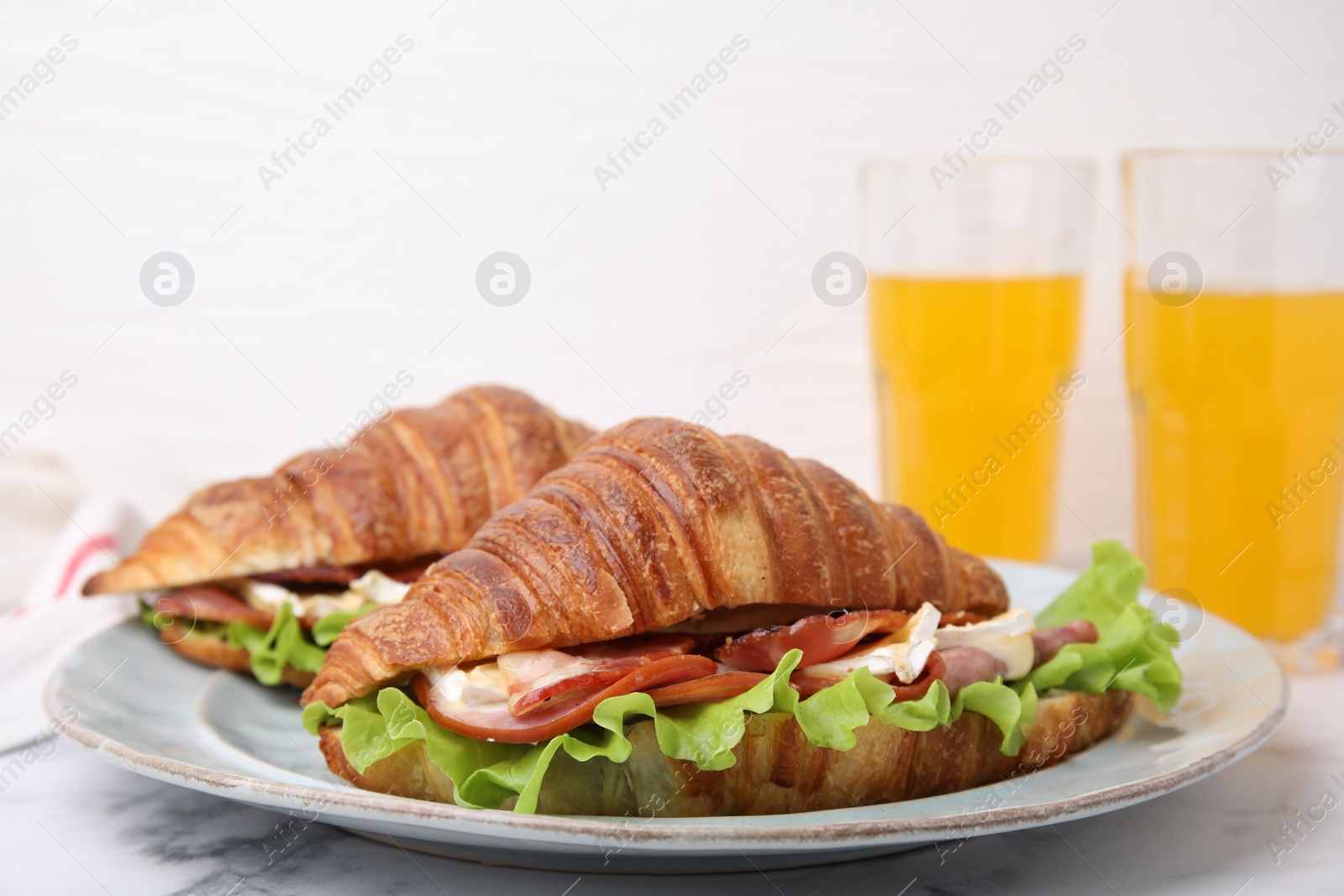 Photo of Tasty croissants with brie cheese, ham and bacon on white marble table, closeup