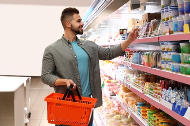 Photo of Young man with shopping basket in supermarket